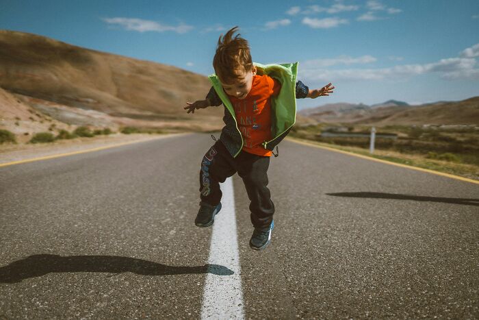 A young boy is jumping in the air on the road
