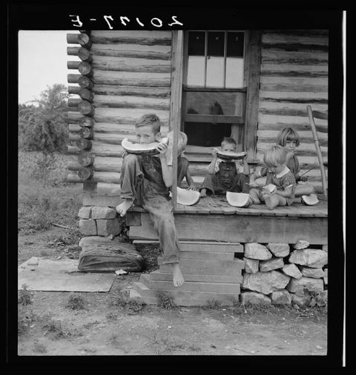 Millworker's Children Eating Watermelon On Porch Of Rented House. Six Miles North Of Roxboro, Person County, North Carolina, 1939. Dorthea Lange
