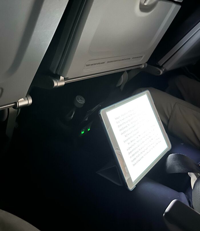 This Person Reading On Their iPad With The Brightness All The Way Up On A 6-Hour Red-Eye Flight