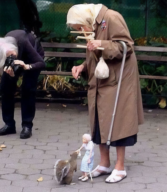 An 85 Year Old Lady Is Feeding A Squirrel In New York's Washington Square Park With A Puppet She Created