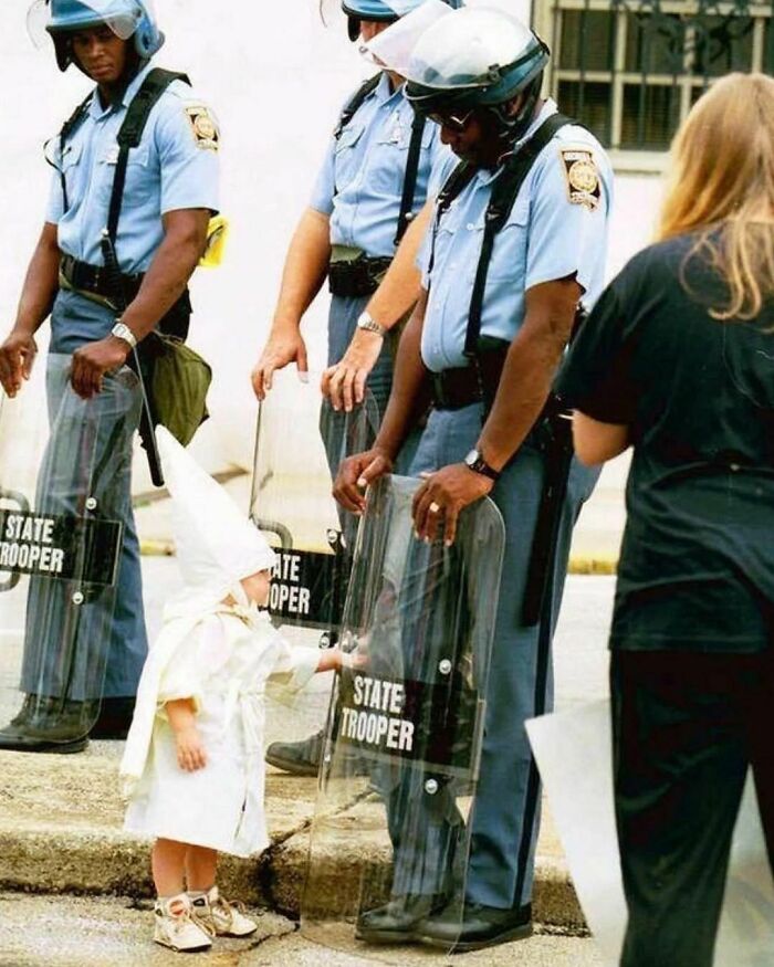 Un niño toca con curiosidad el escudo de un policía estatal, fotografiado por Todd Robertson durante una manifestación del KKK en Georgia, 1992