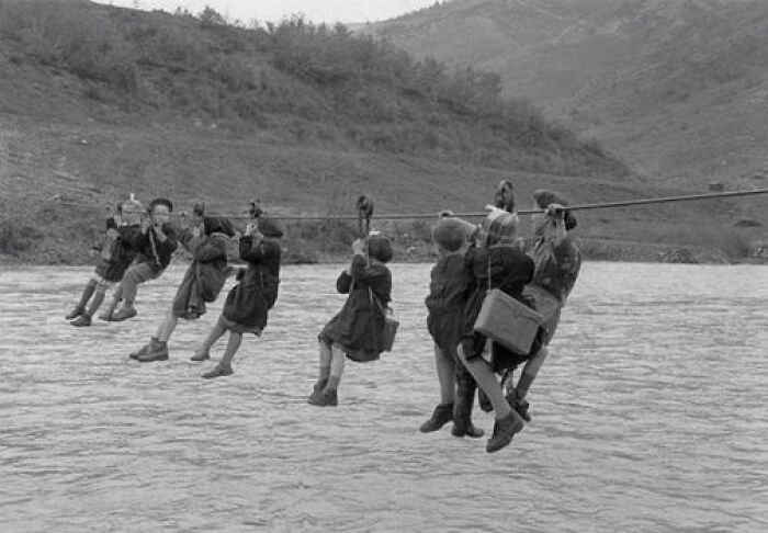 Niños cruzando un río en tirolina para ir al colegio en las afueras de Módena, Italia, 1959
