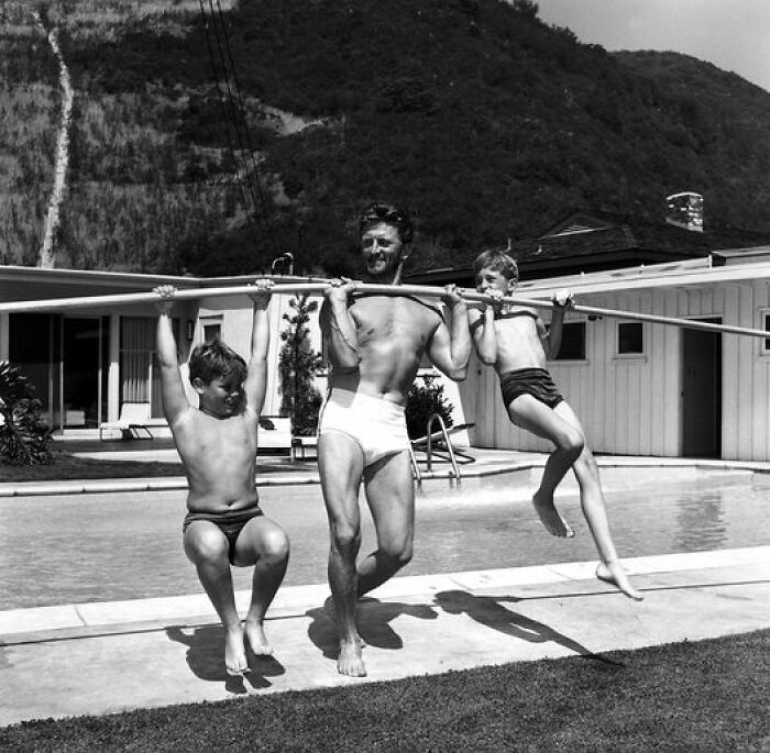 Kirk Douglas levantando a sus hijos con una barra, 1955