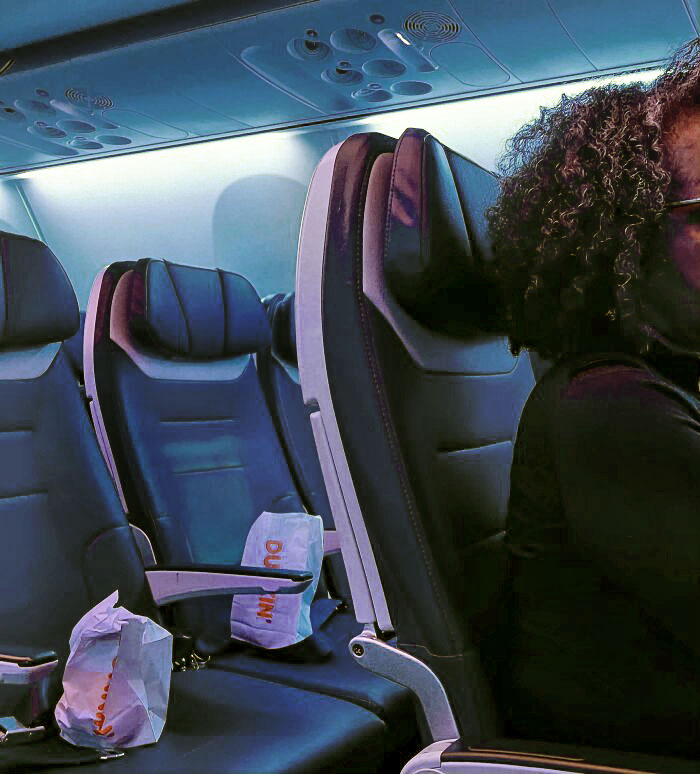 Woman Saving An Entire Row Of Plane Seats Behind Her With Donut Bags