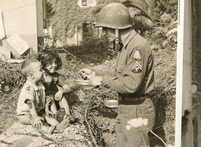 Soldado compartiendo sus raciones con 2 niños italianos, 1944