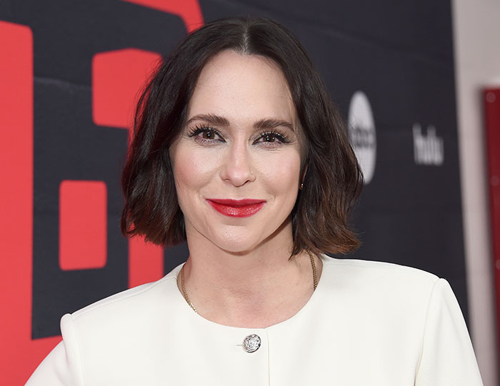 Jennifer Love Hewitt smiling with red lipstick and short dark hair at a media event, introducing her kids to the world. Jennifer Love Hewitt smiling with red lipstick and short dark hair at a media event, introducing her kids to the world.