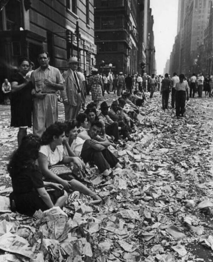 People Sit On A Curb Amid Confetti And Papers After Celebrating The End Of World War II In New York City On August 14, 1945