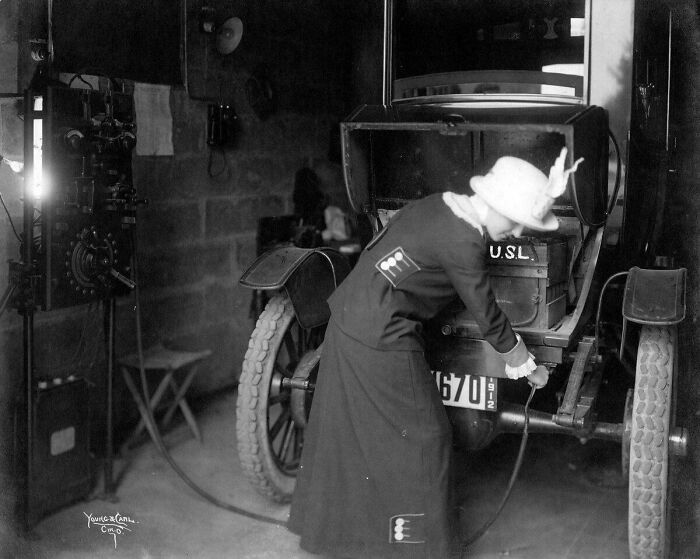 Mujer enchufando su coche eléctrico en 1912