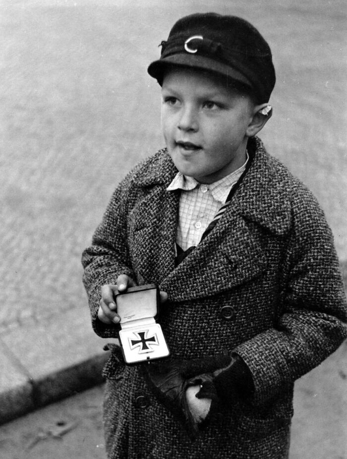 A German Orphan Trying To Sell His Father's Iron Cross For Cigarettes In Berlin, 1945