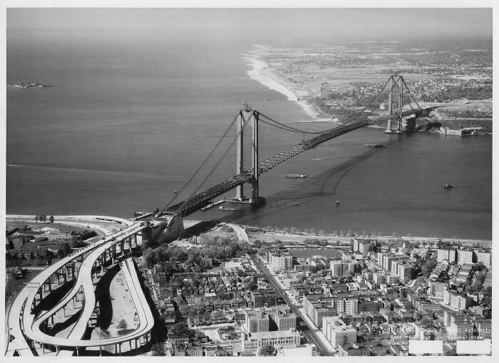 Aerial view of brilliant infrastructure featuring a large suspension bridge under construction spanning a wide river.
