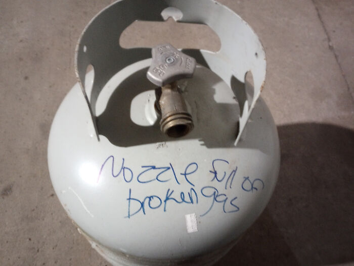 Gas nozzle sign fail with handwritten note on a propane tank.