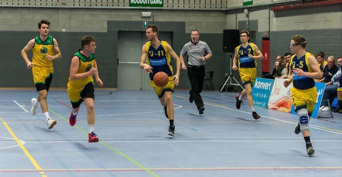 Basketball players in action during a game, capturing a wild coincidence moment on the court with teammates running fast.