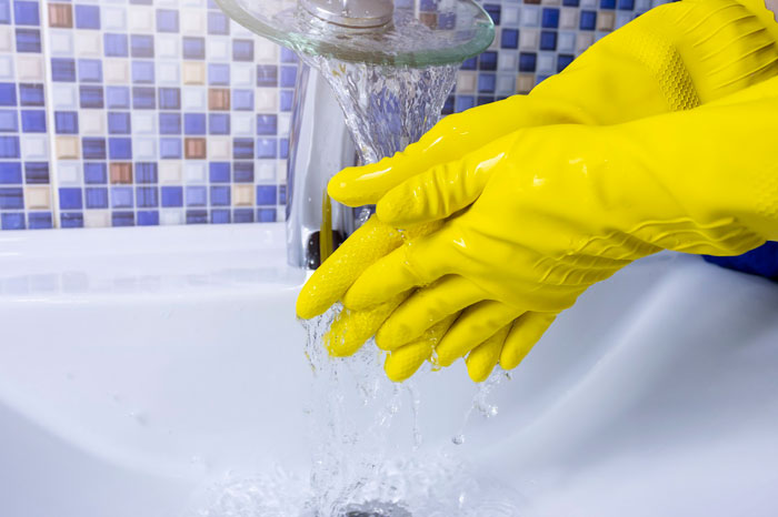 the person washing hands in a yellow rubber gloves