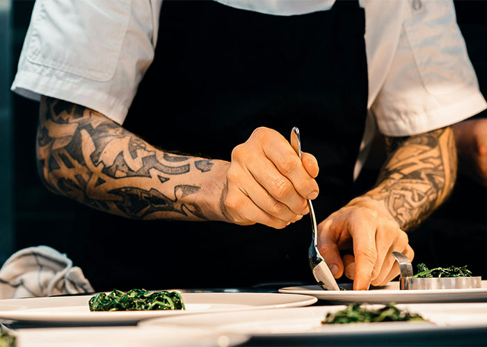 Tattooed machinist's hands preparing food in a kitchen setting. Tattooed machinist's hands preparing food in a kitchen setting.