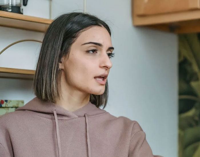 Woman in a beige hoodie looking to the side, expressing surprise and emotion. Woman in a beige hoodie looking to the side, expressing surprise and emotion.