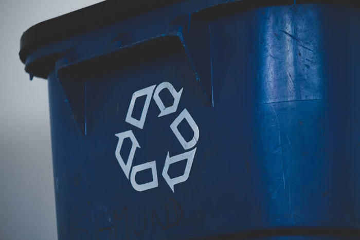 Blue recycling bin with a white recycling symbol on the side. Blue recycling bin with a white recycling symbol on the side.