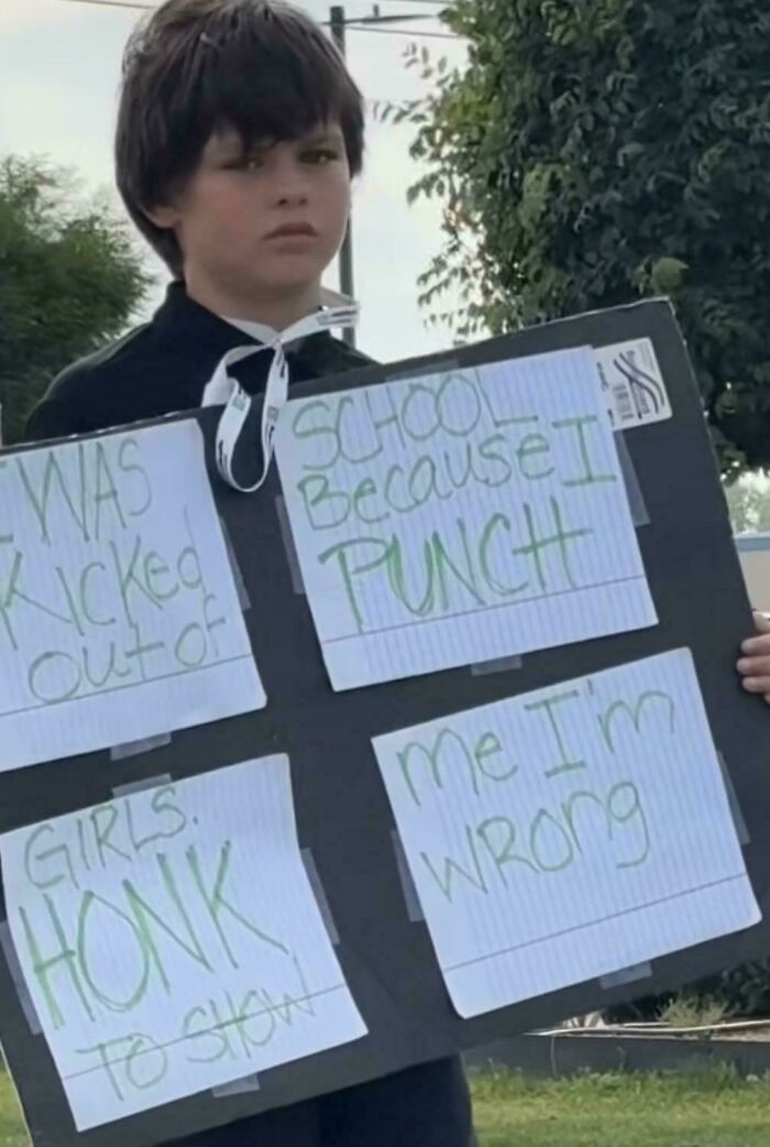 Child holding sign with humorous message, exemplifying sign fails.