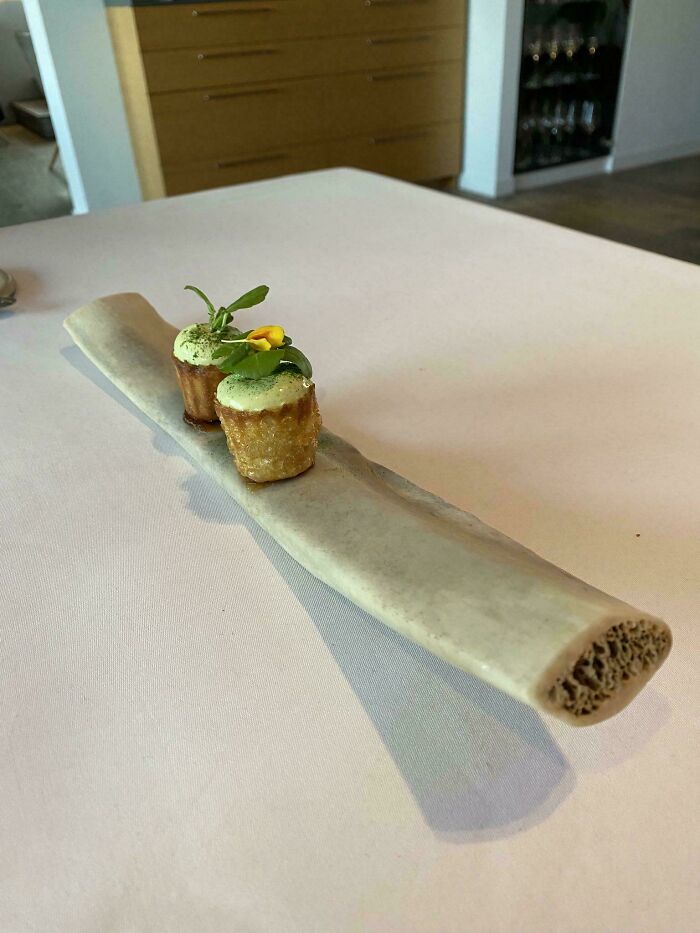 Two bite-sized gourmet appetizers served on a long hollow bone in a creative restaurant food presentation.