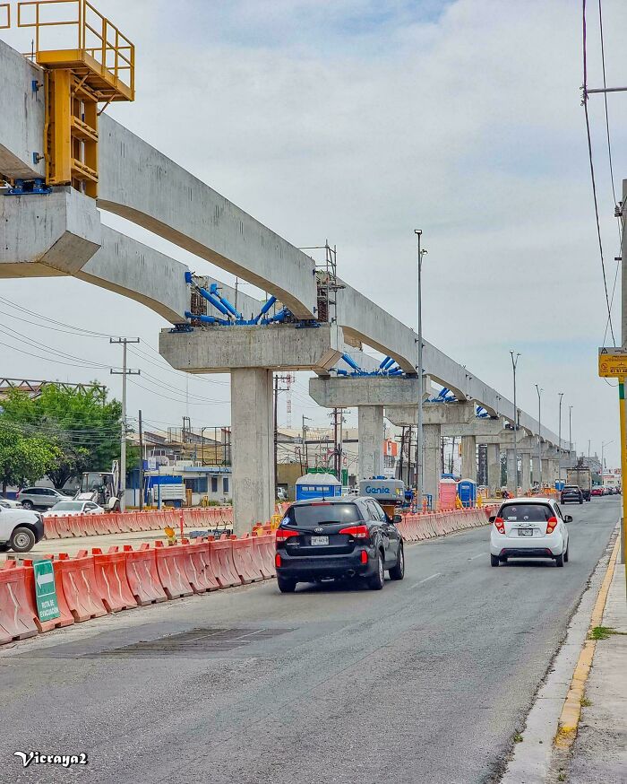 Concrete infrastructure under construction over a city street with cars driving, showcasing brilliant modern urban infrastructure.