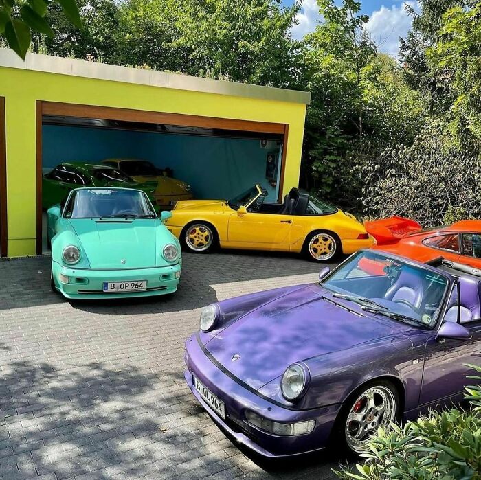 Colorful 1990s cars parked outside a garage, showcasing vibrant automotive design from the decade.