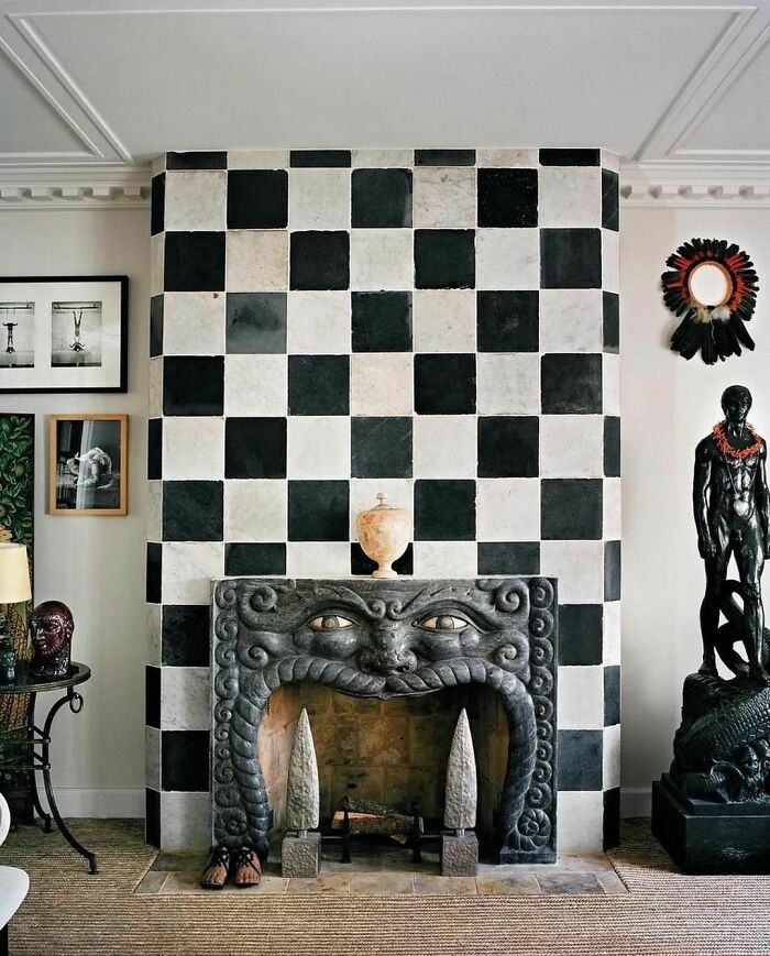 Intricate 1990s fireplace with a checkered wall and decorative sculptures, reflecting nineties design aesthetics.