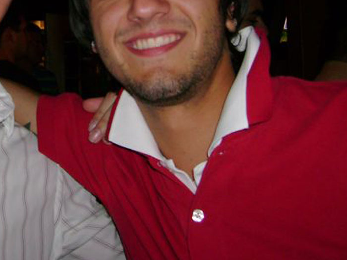 Young man smiling in a red polo shirt with a popped collar, illustrating early 2000s whale tail fashion trend.