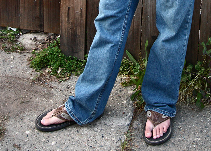 Person wearing baggy jeans and flip-flops showing whale tail trend with low-rise jeans exposed at the back waistband.