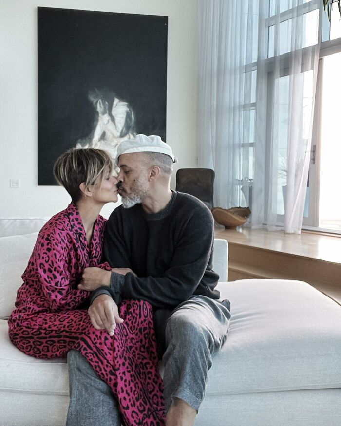 Couple sitting on a couch and sharing a tender moment, with modern art in the background and soft natural light through the windows. Couple sitting on a couch and sharing a tender moment, with modern art in the background and soft natural light through the windows.