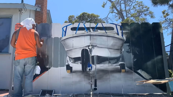 City Forces Guy To Build A Fence To Hide His Boat, He Complies Maliciously And Paints A Mural On It