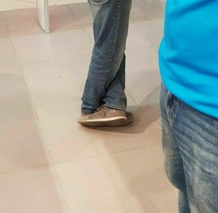 Person wearing casual brown shoes and jeans stepping in an unusual way, captured in a random and cringe photo.
