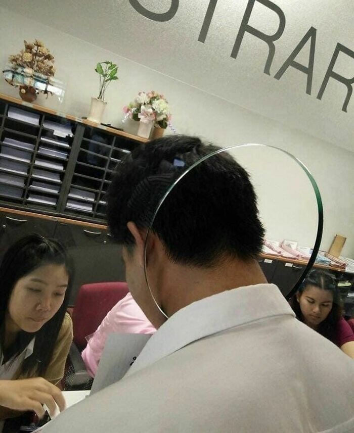 Man wearing a clear face shield in an office, creating a random and cringe moment for those with unique humor.