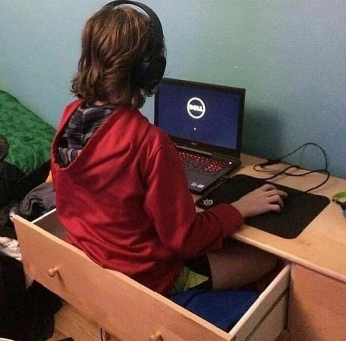 Person wearing red hoodie sitting inside a drawer while using a laptop, a random and cringe photo with unique humor.