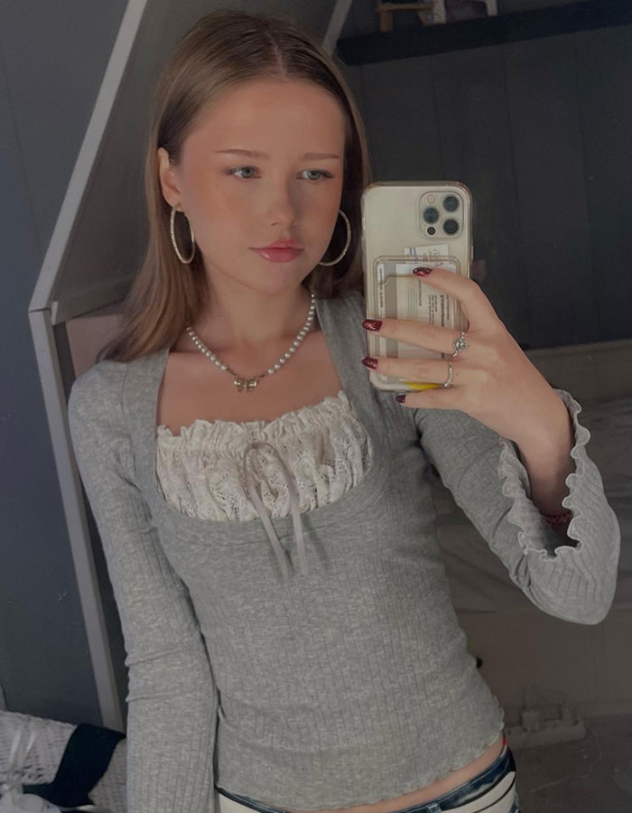 Young woman taking a selfie, appearing baffled as strangers have a picnic in her yard in the background. Young woman taking a selfie, appearing baffled as strangers have a picnic in her yard in the background.