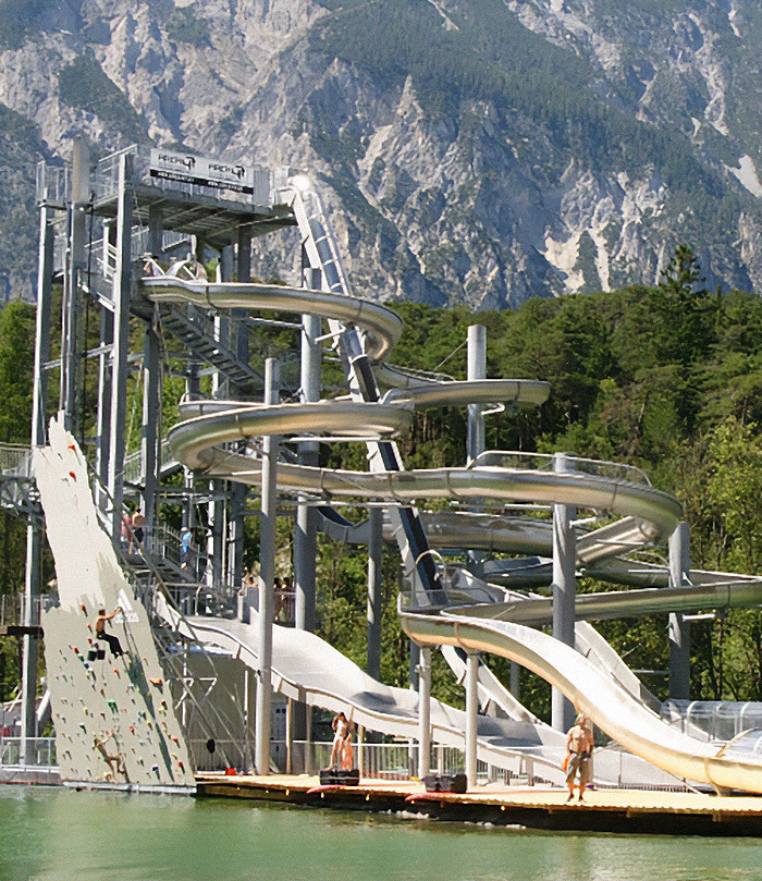 Extreme waterslide with thrill-seeking diver jumping down, surrounded by mountainous landscape and dense forest backdrop. Extreme waterslide with thrill-seeking diver jumping down, surrounded by mountainous landscape and dense forest backdrop.