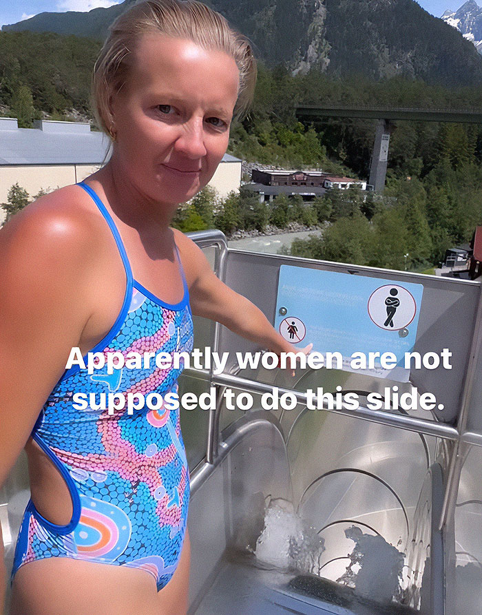 Woman in a colorful swimsuit at the top of an extreme waterslide, challenging the strict ban for women to ride. Woman in a colorful swimsuit at the top of an extreme waterslide, challenging the strict ban for women to ride.