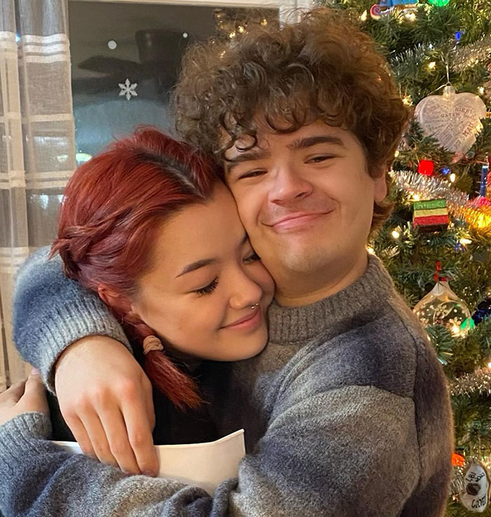 Two people hugging next to a decorated Christmas tree, embodying a warm holiday moment. Two people hugging next to a decorated Christmas tree, embodying a warm holiday moment.
