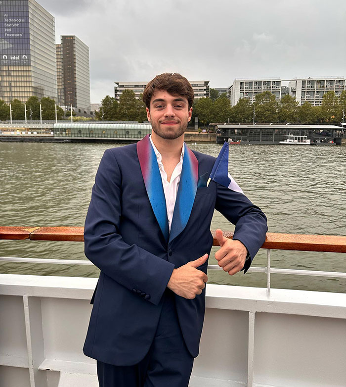 French diver on a boat, wearing a blue suit with a colorful lapel, standing with a thumbs up by the river. French diver on a boat, wearing a blue suit with a colorful lapel, standing with a thumbs up by the river.