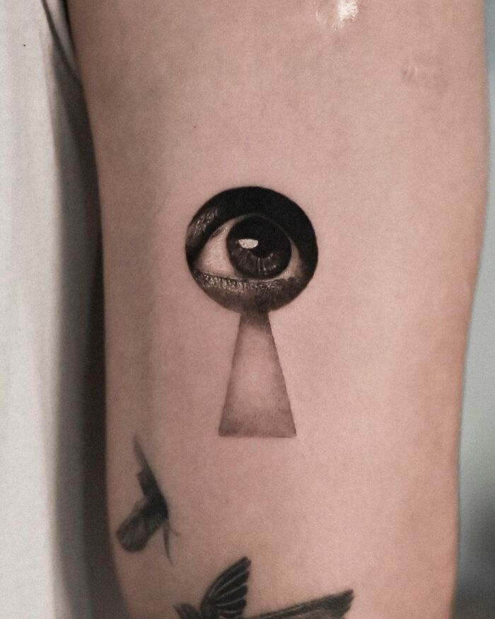 Hyperrealistic tattoo of an eye inside a keyhole on an arm, showcasing detailed artistry. Hyperrealistic tattoo of an eye inside a keyhole on an arm, showcasing detailed artistry.