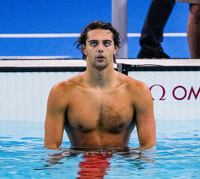 Gold medalist swimmer standing in the pool after a race, facing the camera. Gold medalist swimmer standing in the pool after a race, facing the camera.
