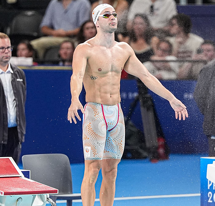 Dutch swimmer at 2024 Olympics wearing striking trunks, surrounded by spectators and preparing to compete. Dutch swimmer at 2024 Olympics wearing striking trunks, surrounded by spectators and preparing to compete.
