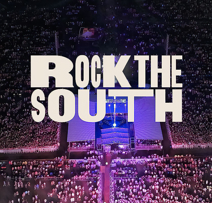 Aerial view of a concert with large crowd and stage, "Rock the South" logo prominently displayed. Aerial view of a concert with large crowd and stage, "Rock the South" logo prominently displayed.