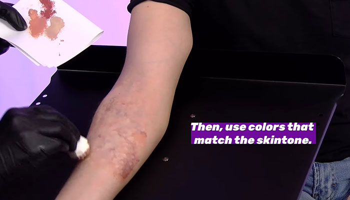 Makeup artist covering up a tattoo on an arm with skin-toned makeup. Makeup artist covering up a tattoo on an arm with skin-toned makeup.