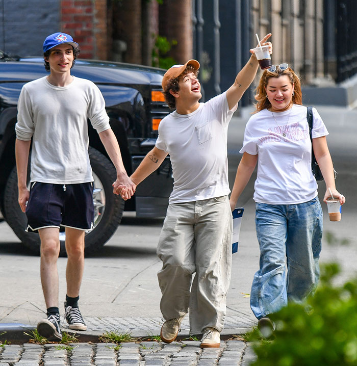 Stranger Things stars walking together in New York, holding hands, dressed casually, holding drinks. Stranger Things stars walking together in New York, holding hands, dressed casually, holding drinks.