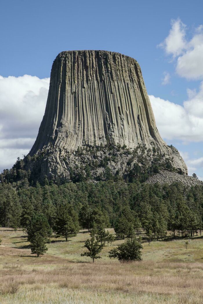 Massive towering rock formation rising above forest, illustrating fear for those with megalophobia.