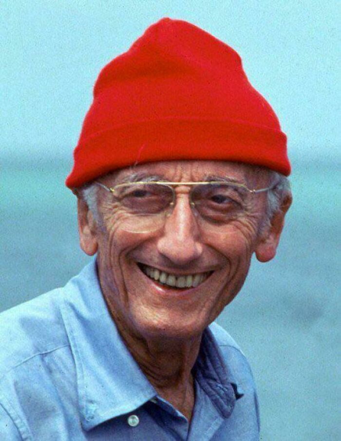 Elderly man smiling with a red beanie and glasses, evoking nostalgic memories of creaking joints and aging.