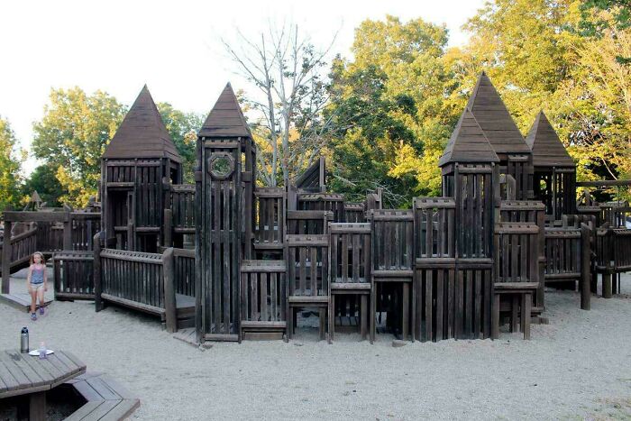 Large wooden playground structure with towers and slides, a nostalgic item reminding you of your creaking joints.