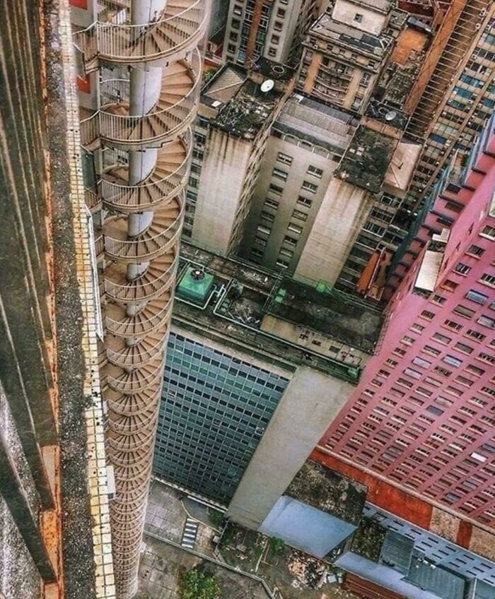 View looking down a tall building with a spiral fire escape causing fear for those with megalophobia.