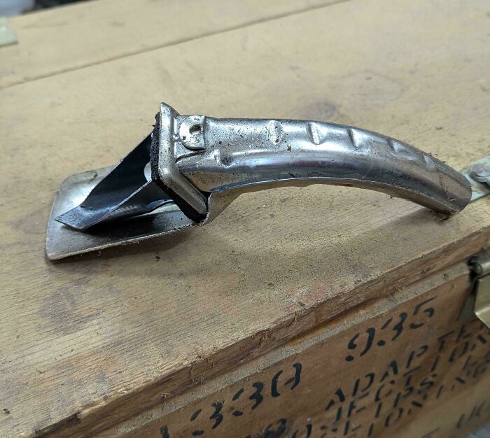 Vintage metal can opener with curved handle placed on a wooden crate, evoking nostalgia and creaking joints memories.