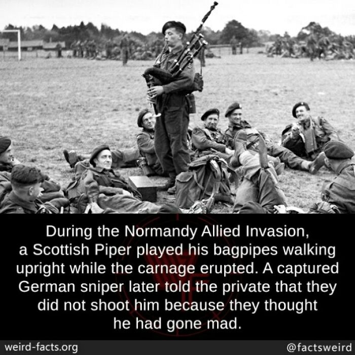 Black and white photo of a Scottish Piper playing bagpipes during WWII Normandy invasion with soldiers resting nearby.