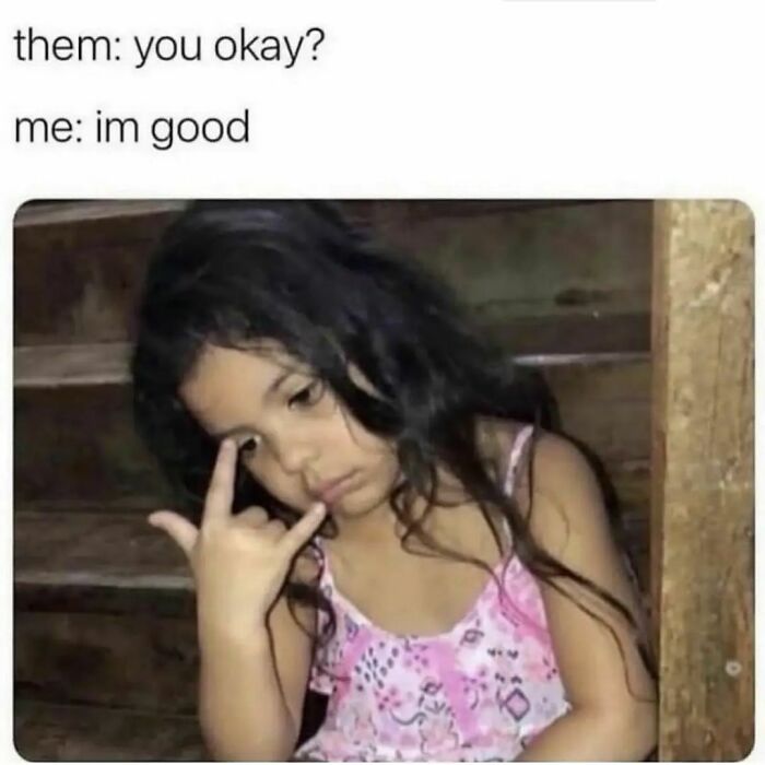 Sad young girl in a pink dress making a hand gesture in a relatable work stress meme about pretending to be okay.